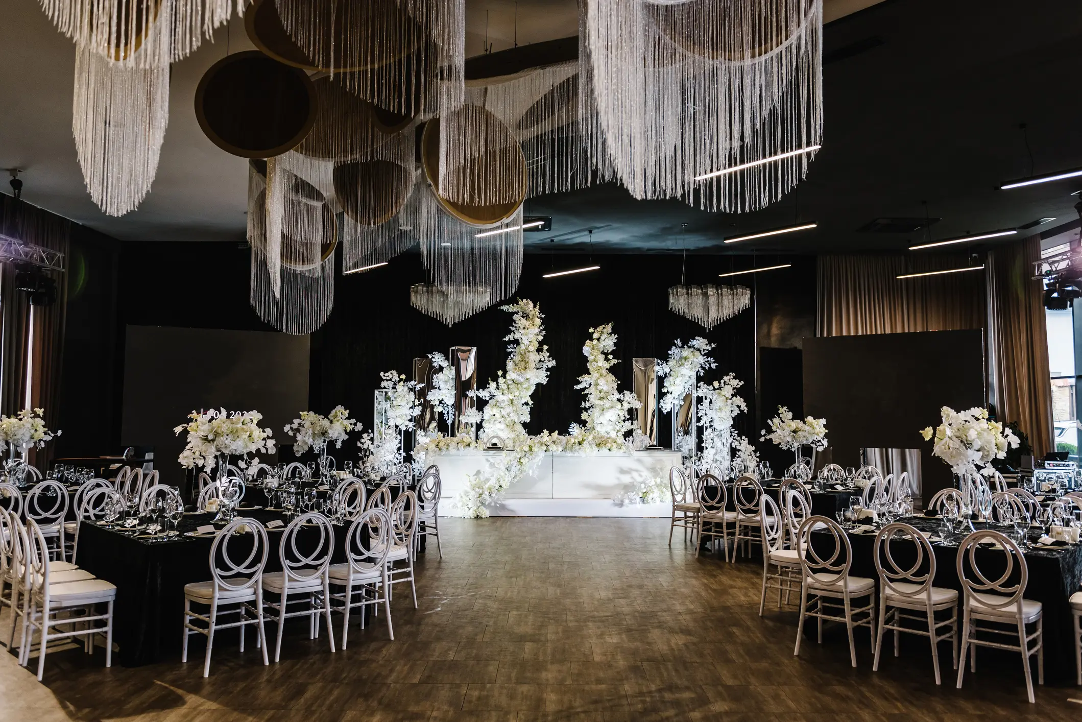 Festive tables with flower composition on black tablecloth and chairs for guests. Wedding set up, dinner table reception in area on party. Banquet decoration in hall restaurant. Setting. Side view.
